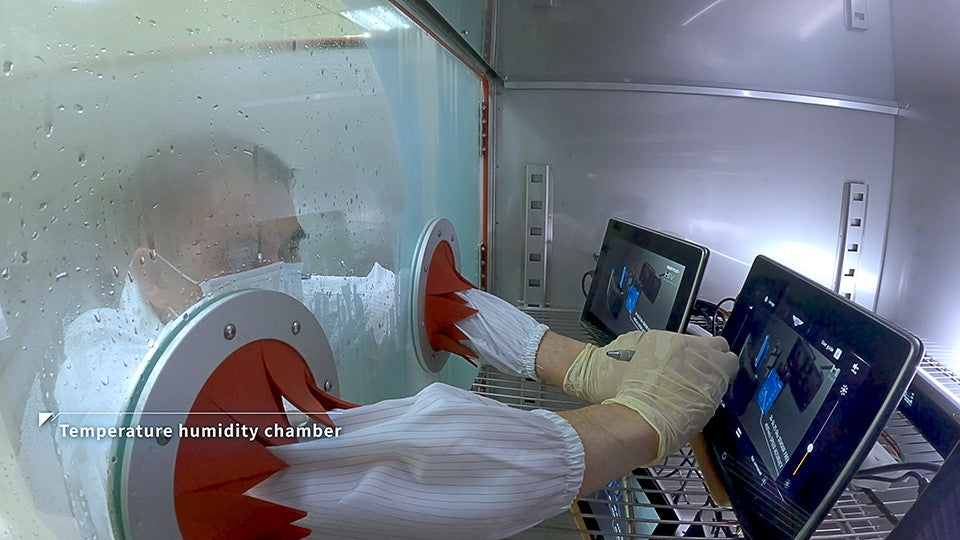 Technician operating displays inside a temperature and humidity chamber through glove ports